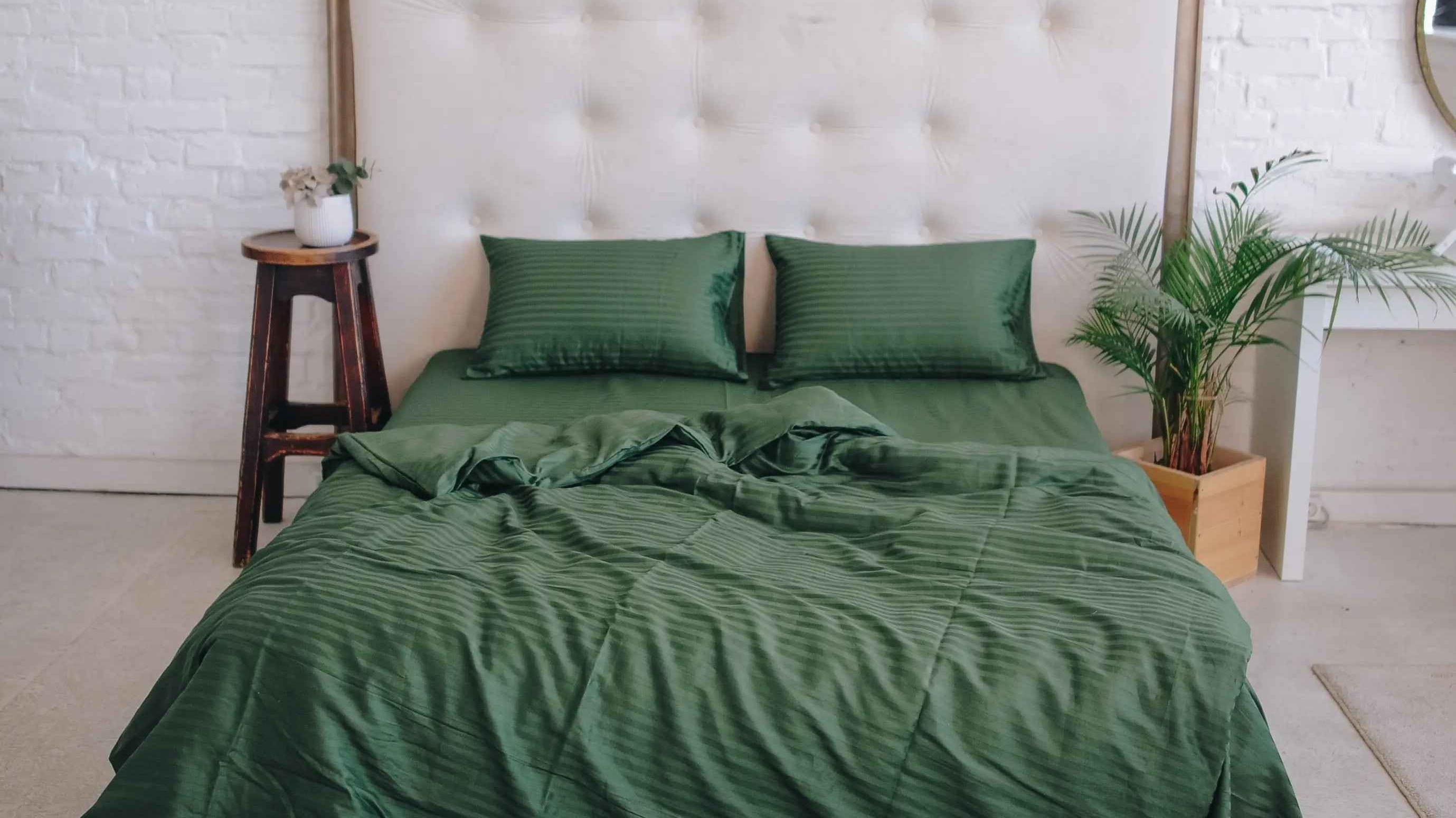 Pościel butelkowa zieleń na łóżku z beżowym zagłówkiem w nowoczesnej sypialni.