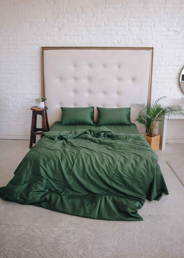 Pościel butelkowa zieleń na łóżku z beżowym zagłówkiem w nowoczesnej sypialni.